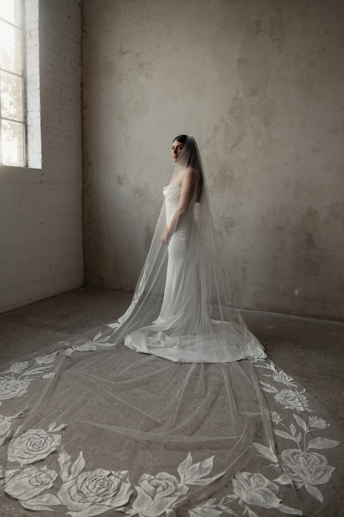 Bride wearing a chapel-length wedding veil beside a bride wearing a cathedral-length wedding veil, illustrating the difference in veil lengths.