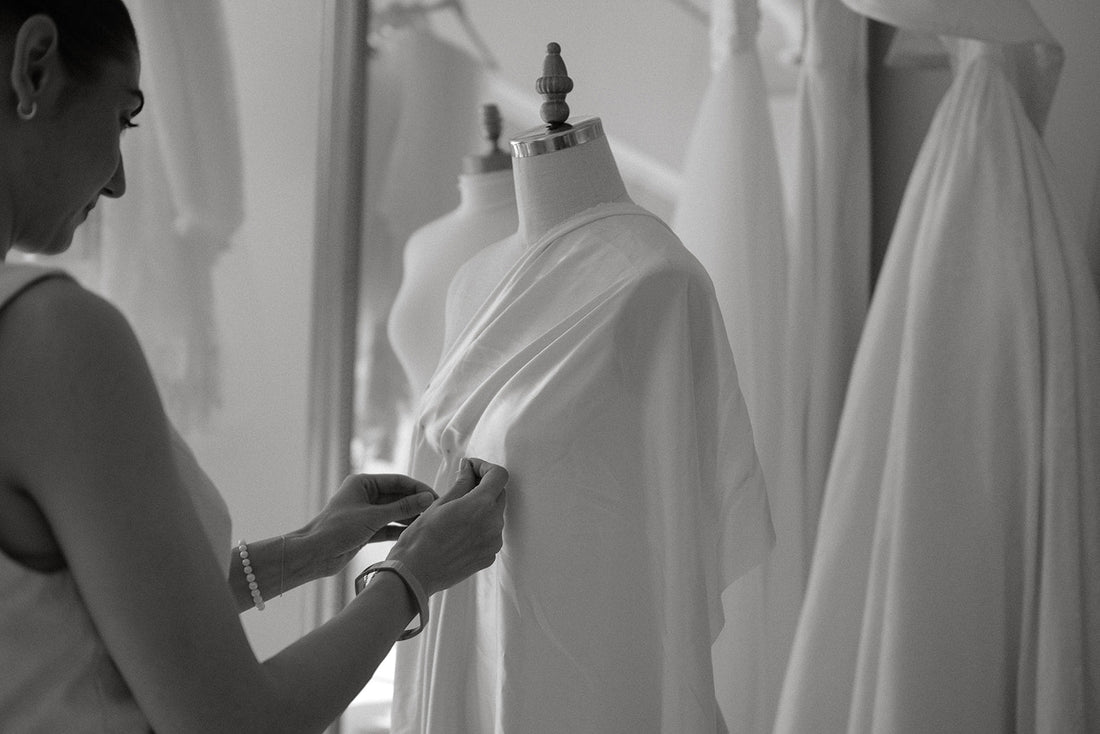Atelier Caravaggio designer, Erin Caravaggio, drapes silk charmeuse over a mannequin, creating pleats that she then pins.